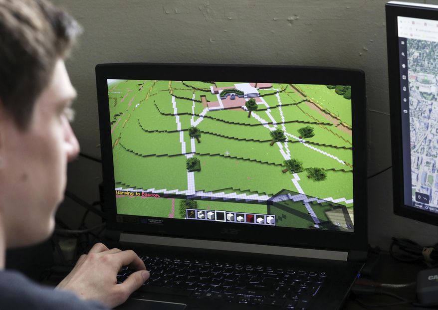 In this April 23, 2020, photo, UW-Madison graduate Zach Powers works on virtually building Bascom Hall in Minecraft at his apartment in Madison, Wis. Student organizations hold Zoom meetings and the Wisconsin Union created coloring pages. The Office of Sustainability moved the recent Earth Day celebrations online, including do-it-yourself crafts and yoga held over Facebook Live. An informal group of students and alumni are virtually creating the campus on Minecraft, a popular video game where users construct buildings and communities. On tap is a university-wide virtual festival for students to listen to a cappella groups, play Badger trivia and more. (Amber Arnold/Wisconsin State Journal via AP)