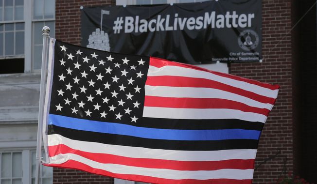 FILE - In this July 28, 2016, file photo, a flag with a blue and black stripes in support of law enforcement officers, flies at a protest by police and their supporters outside Somerville City Hall in Somerville, Mass. San Francisco&#x27;s police chief said the city&#x27;s rank and file will wear neutral face coverings to defuse a controversy that was sparked when officers sent to patrol a May Day protest wore masks adorned with the &amp;quot;thin blue line&amp;quot; flag. (AP Photo/Charles Krupa, File)