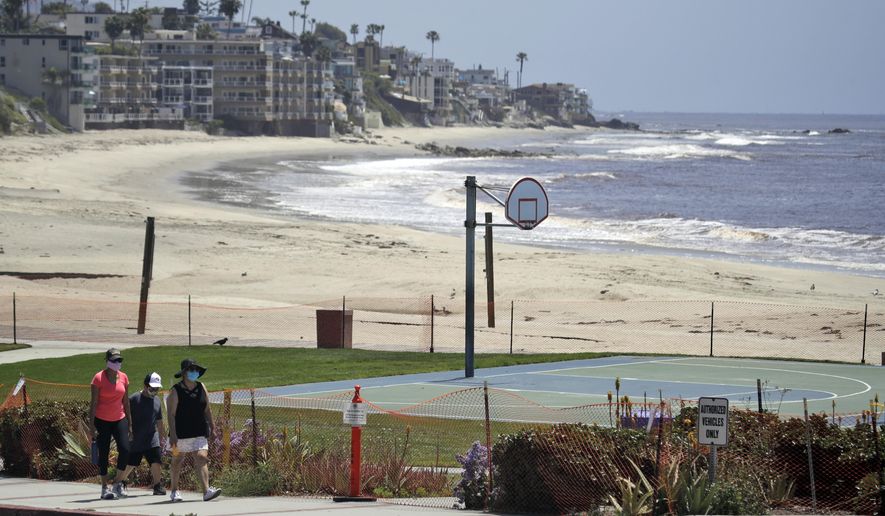 FILE - In this May 3, 2020 file photo people walk past a closed off beach, in Laguna Beach, Calif. Two Orange County cities can start reopening their beaches Monday, May 4, 2020, after they submitted plans to avoid overcrowding and allow for physical distancing in an effort to prevent the spread of the coronavirus, state officials said. The cities of Laguna Beach and San Clemente both submitted plans to reopen their beaches that adhere to California Gov. Gavin Newsom's stay-at-home order, the California Natural Resources Agency said in a statement. (AP Photo/Marcio Jose Sanchez,File)