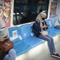 Commuters wearing protective mask use their smartphone in a Mass Rapid Transit train, in Kuala Lumpur, Malaysia, on Monday, May 4, 2020. Many business sectors reopened Monday in some parts of Malaysia since a partial virus lockdown began March 18. (AP Photo/Vincent Thian)