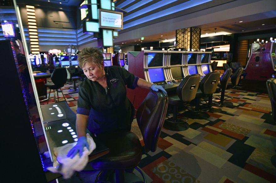 FILE - In this March 18, 2020, file photo, Antonia Garcia cleans slot machines inside the Planet Hollywood hotel-casino in Las Vegas. When shuttered casinos reopen in Nevada, patron counts will be cut in half, nightclubs will remain closed, convention groups will be limited and gamblers will have to keep safe distances apart. Nevada Gaming Control Board Chairwoman Sandra Douglass Morgan said Monday, May 4, 2020, the state is going to require a lot before letting casinos and resort operators reopen. Gov. Steve Sisolak has not announced a target date. (AP Photo/David Becker, File)