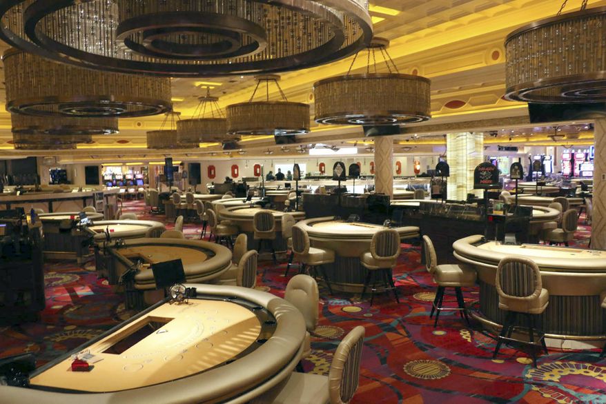 FILE - In this March 18, 2020, file photo, empty gaming tables are viewed at The Peppermill Resort Spa & Casino in Reno, Nev. When shuttered casinos reopen in Nevada, patron counts will be cut in half, nightclubs will remain closed, convention groups will be limited and gamblers will have to keep safe distances apart. Nevada Gaming Control Board Chairwoman Sandra Douglass Morgan said Monday, May 4, 2020, the state is going to require a lot before letting casinos and resort operators reopen. Gov. Steve Sisolak has not announced a target date. (Jason Bean/Reno Gazette-Journal via AP, File)