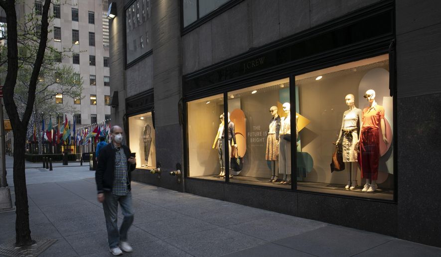 A man wearing a mask walks by a window display at a J.Crew store in Rockefeller Center, Saturday, May 2, 2020, in New York. On April 30, the company announced it would apply for bankruptcy protection amidst the COVID-19 pandemic. (AP Photo/Mark Lennihan)