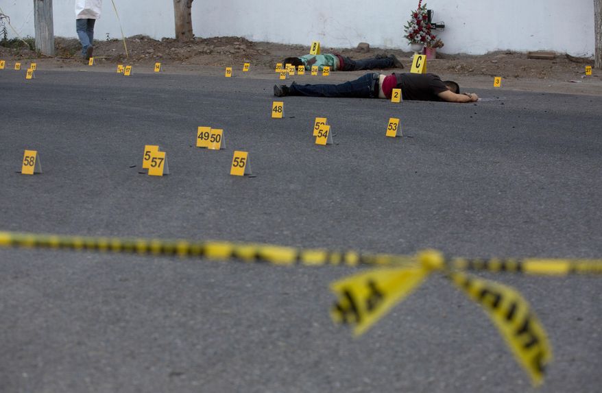 FILE - In this June 29, 2017 file photo, investigators mark the spot where spent bullet casing fell next several bodies lying on a road in the town of Navolato, Sinaloa state, Mexico. For people in Mexican towns and villages where criminal gangs, armed groups and drug traffickers hold more sway than the state, the novel coronavirus is just the latest danger. The threat of death and the inability to move freely are nothing new. (AP Photo/Enric Marti, File)