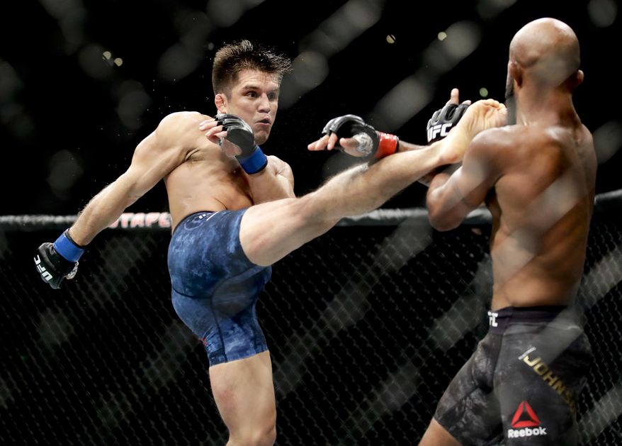 FILE - In this Aug. 4, 2018, file photo, Henry Cejudo, left, kicks Demetrious Johnson during their UFC flyweight title mixed martial arts bout at UFC 227 in Los Angeles. Cejudo is scheduled to fight Dominick Cruz at UFC 249 in Jacksonville, Fla., on Saturday, May 9, 2020. (AP Photo/Chris Carlson, File)