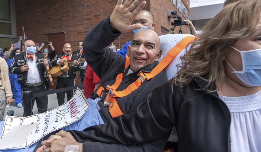 In this Monday, May 4, 2020, photo, provided by The Permanente Federation, Hector Calderon, joined by his wife, waves to well-wishers as a Mariachi band plays as he's discharged from Kaiser Permanente Westside Medical Center in Hillsboro, Ore. Calderon spent many days in the intensive care unit, where he was sedated and intubated, before he recovered enough to be transferred to a skilled nursing facility on Monday, May 4, 2020. He was listed as the state's first confirmed new coronavirus case on Feb. 28. (Jan Sonnenmair/The Permanente Federation via AP)