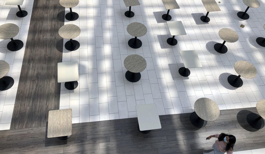 A woman wearing a protective mask walks through the mostly empty food court as Alabama's largest shopping mall, the Riverchase Galleria reopened in Hoover, Ala., Tuesday, May 5, 2020. Dozens of stores, including major retailers, remained closed as the mall opened for business for the first time during the coronavirus pandemic. (AP Photo/Jay Reeves)