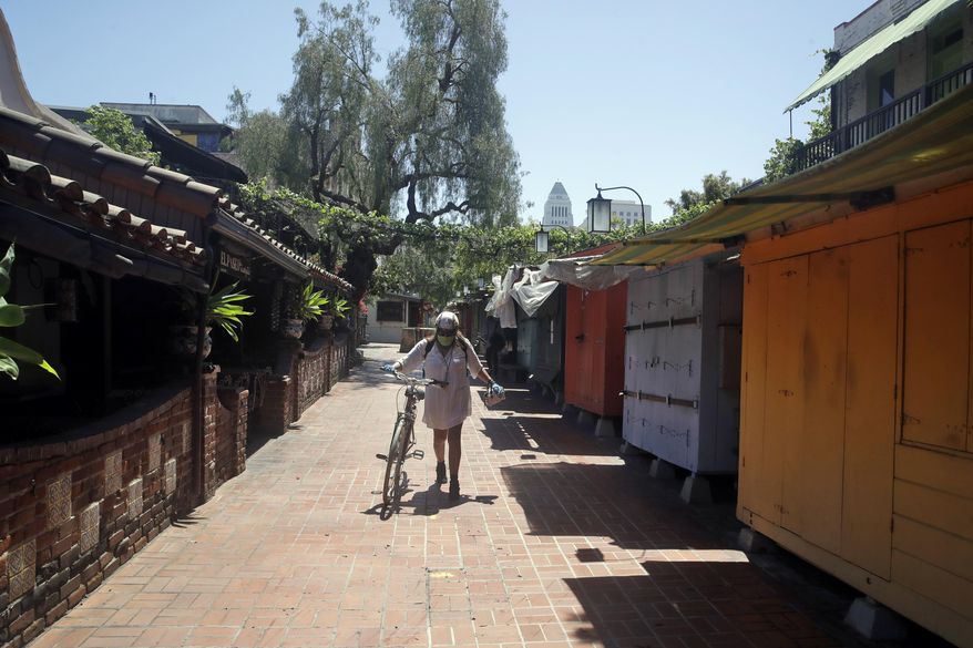 Christine Olivarri walks along the shuttered shops on Olvera Street amid the COVID-19 pandemic Tuesday, May 5, 2020, in Los Angeles. (AP Photo/Marcio Jose Sanchez)