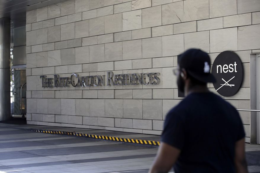 A person walks past the Ritz-Carlton Tuesday, May 5, 2020, in Los Angeles. A Los Angeles councilman says luxury hotels should not be exempt from a program to temporarily move people experiencing homelessness into empty hotel rooms after owners at the city's Ritz-Carlton said they opposed the plan. (AP Photo/Marcio Jose Sanchez)