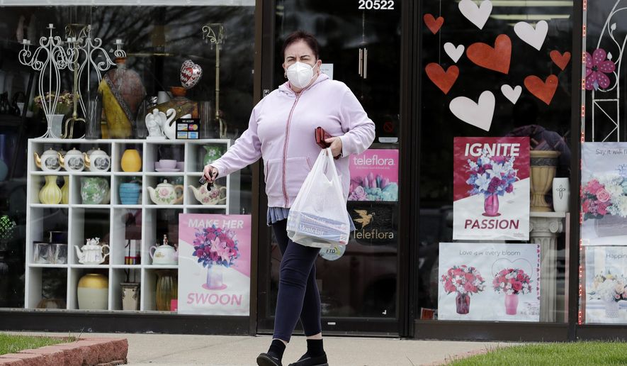 A woman wears mask as she leaves a store during the coronavirus pandemic in Deerfield, Ill., Tuesday, May 5, 2020. New Illinois rules about wearing a face mask over age 2 start Friday, May 1, when they can't maintain a 6 foot social distance in public. (AP Photo/Nam Y. Huh)