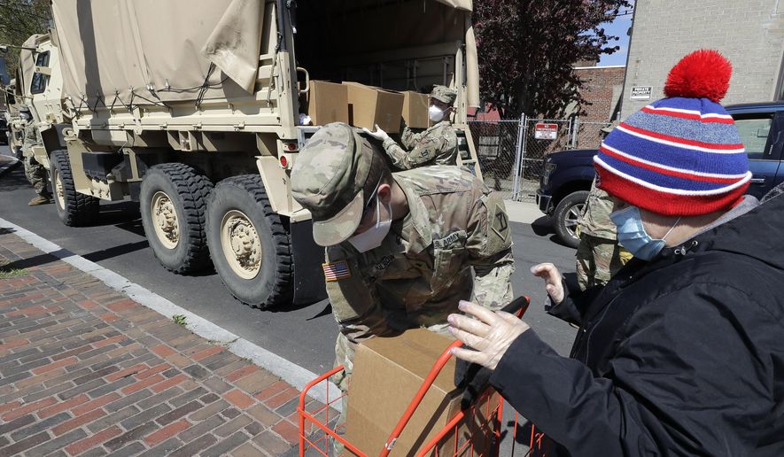 Massachusetts National Guard soldiers from the 181st Engineer Company, left, wear masks out of concern for the coronavirus as they distribute boxes of food, Tuesday, May 5, 2020, to people also wearing masks, in Chelsea, Mass. (AP Photo/Steven Senne)