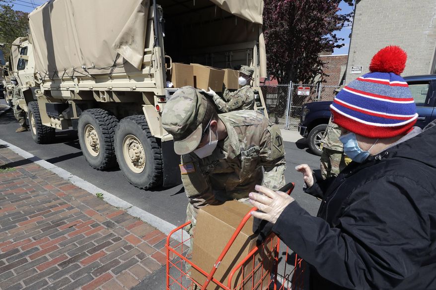 Massachusetts National Guard soldiers from the 181st Engineer Company, left, wear masks out of concern for the coronavirus as they distribute boxes of food, Tuesday, May 5, 2020, to people also wearing masks, in Chelsea, Mass. (AP Photo/Steven Senne)
