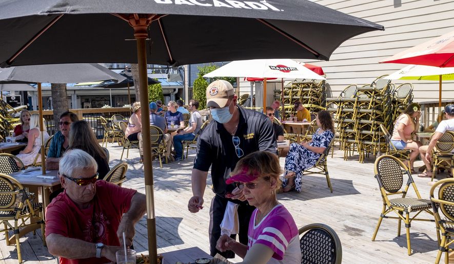 Servers wearing masks wait on customers on the deck of Dead Dog Saloon in Murrells Inlet, S.C. Rules for outdoor dining in South Carolina amid the coronavirus were relaxed on Monday. May 4, 2020. (Jason Lee/The Sun News via AP)