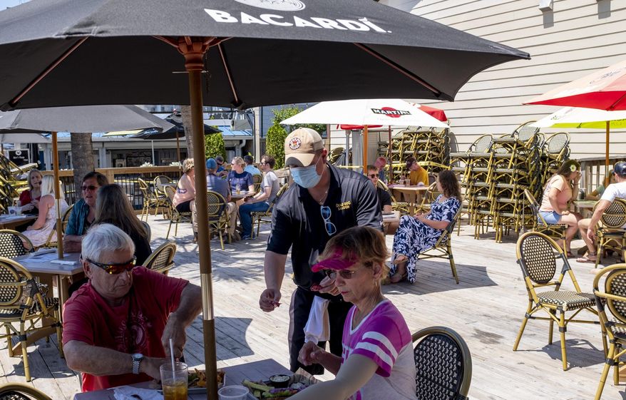 Servers wearing masks wait on customers on the deck of Dead Dog Saloon in Murrells Inlet, S.C. Rules for outdoor dining in South Carolina amid the coronavirus were relaxed on Monday. May 4, 2020. (Jason Lee/The Sun News via AP)