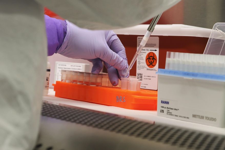 FILE - In this March 3, 2020, file photo, Hawaii state Department of Health microbiologist Mark Nagata demonstrates the process for testing a sample for coronavirus at the department's laboratory in Pearl City, Hawaii. An Associated Press analysis shows that some of the least-populated states, such as Hawaii, with relatively few coronavirus cases received an out-sized proportion of the $150 billion in federal money that was designed to address virus-related expenses. (AP Photo/Audrey McAvoy, File)