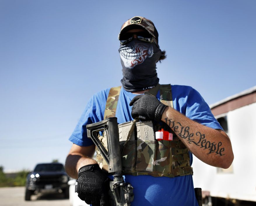 Armed protester Wyatt Winn waits for Ector County Sheriff's officers and Texas State Troopers, who were monitoring a protest, shortly before his arrest Monday, May 4, 2020, at Big Daddy Zane's bar near Odessa, Texas. Winn and others were supporting the the bar's owner, who decided to open despite orders from the Texas governor during the coronavirus pandemic that prohibit the opening until later in May. (Eli Hartman/Odessa American via AP)