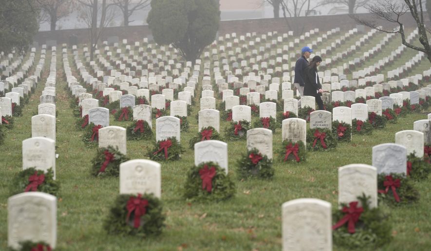 In this Dec. 14, 2019, photo, people walk among headstones with holiday wreaths in Arlington National Cemetery during Wreaths Across America Day in Arlington, Va. (AP Photo/Sait Serkan Gurbuz) **FILE**