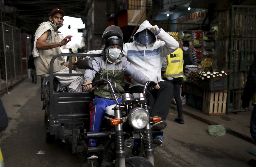 Men wearing face masks ride a motorcycle that hauls a trailer in the “Villa 31” neighborhood during a government-ordered lockdown to curb the spread of the new coronavirus in Buenos Aires, Argentina, Tuesday, May 5, 2020. According to official data, the number of confirmed cases of COVID-19 disease in this city’s slum have increased in the past week, putting authorities on high alert. (AP Photo/Natacha Pisarenko)