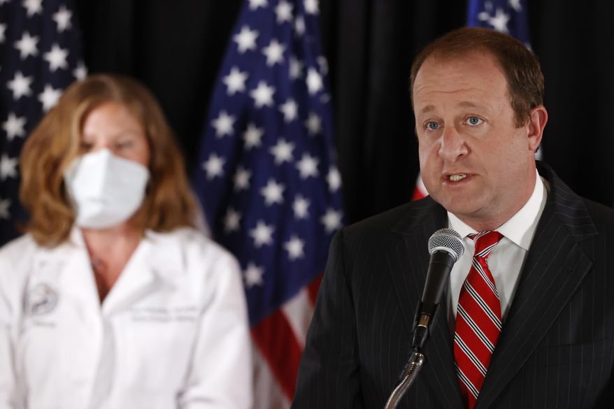 Colorado Governor Jared Polis, front, makes a point as nurse Laura Rosenthal of the University of Colorado School of Medicine looks on during a news conference to update reporters on the state's efforts to stem the rise of the new coronavirus Wednesday, May 6, 2020, in Denver. (AP Photo/David Zalubowski)