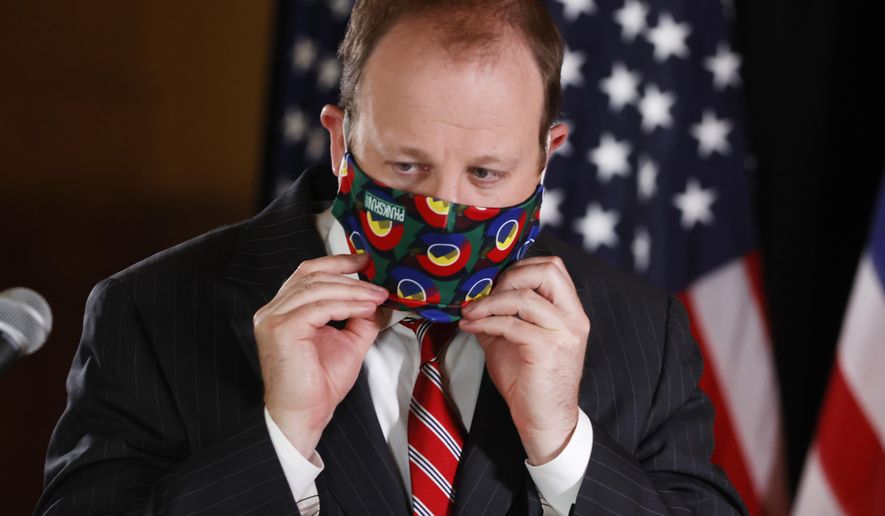 Colorado Governor Jared Polis pulls on his face mask during a news conference to update reporters on the state's efforts to stem the rise of the new coronavirus Wednesday, May 6, 2020, in Denver. (AP Photo/David Zalubowski)