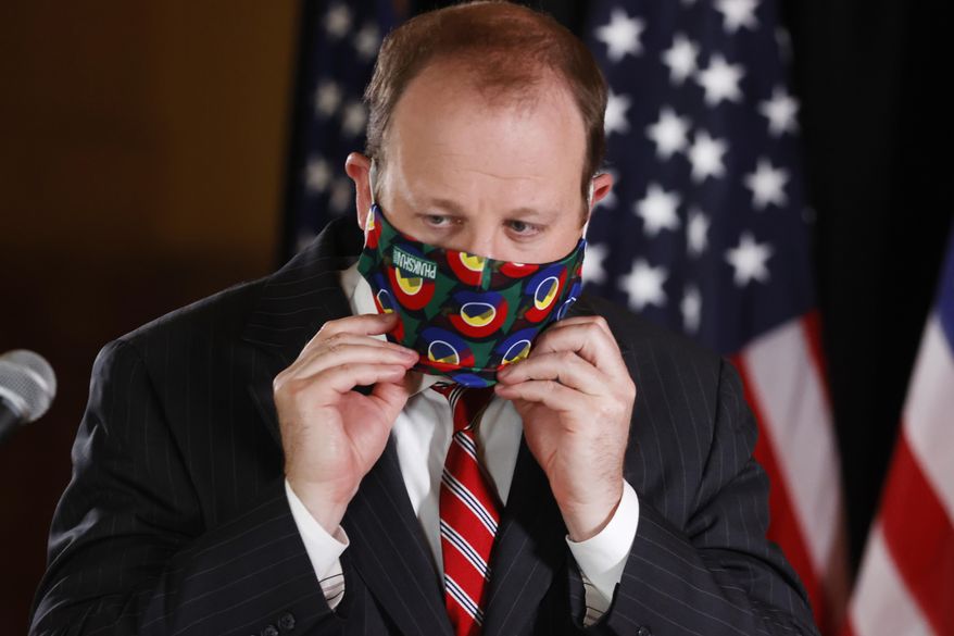 Colorado Governor Jared Polis pulls on his face mask during a news conference to update reporters on the state's efforts to stem the rise of the new coronavirus Wednesday, May 6, 2020, in Denver. (AP Photo/David Zalubowski)