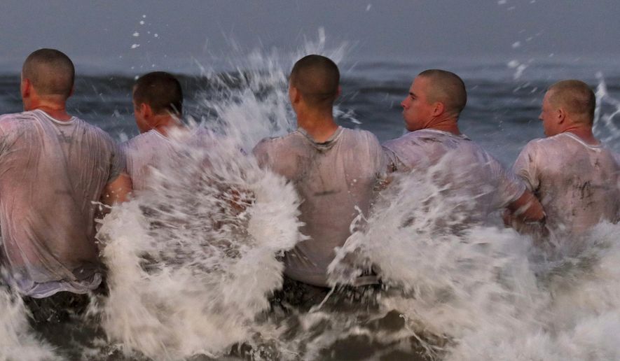 This Monday May 4, 2020, photo provided by the U.S. Navy shows SEAL candidates participating in &quot;surf immersion&quot; during Basic Underwater Demolition training at the Naval Special Warfare (NSW) Center in Coronado, Calif. Navy SEAL recruits and their instructors are being tested for the coronavirus as the candidates in one of the military&#x27;s most grueling programs return to training with new social distancing guidelines, a top official said Tuesday, May 5, 2020. (MC1 Anthony Walker/U.S. Navy via AP)