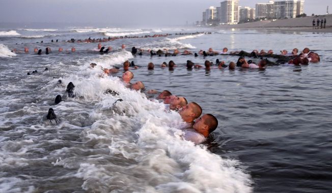 This Monday May 4, 2020, photo provided by the U.S. Navy shows SEAL candidates participating in &amp;quot;surf immersion&amp;quot; during Basic Underwater Demolition/SEAL (BUD/S) training at the Naval Special Warfare (NSW) Center in Coronado, Calif. Navy SEAL recruits and their instructors are being tested for the coronavirus as the candidates in one of the military&#x27;s most grueling programs return to training with new social distancing guidelines, a top official said Tuesday, May 5, 2020. (MC1 Anthony Walker/U.S. Navy via AP)