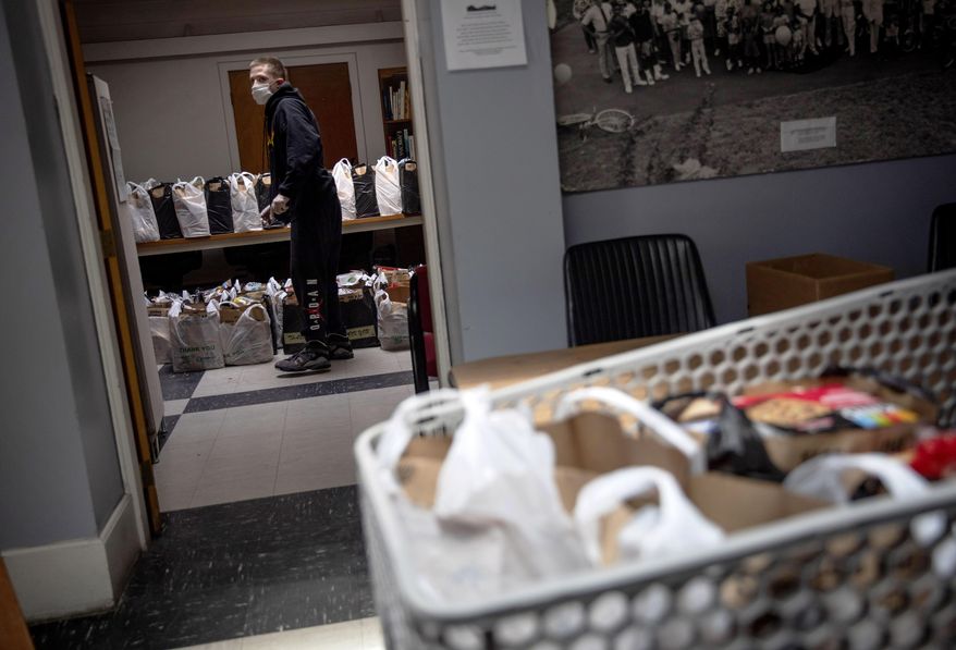 Brian Vanasse lines up bags of food at the Mount Hope Community Center to be distributed to families in need, Wednesday, May 6, 2020, in Providence, R.I. The community center has increased their food distribution about 350 percent from when the coronavirus first shutdown the state in mid-March. (AP Photo/David Goldman)
