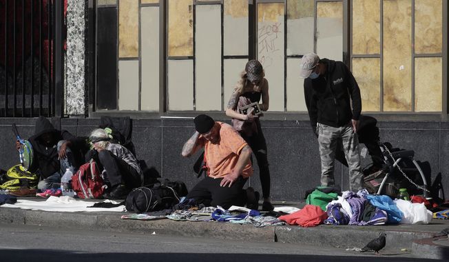 In this April 21, 2020, file photo, people sit and gather with belongings on a sidewalk in San Francisco. There are no tourists anymore on San Francisco&#x27;s famously twisty and steep Lombard Street. The city&#x27;s landmark hotels and posh shops are boarded up tight. But one staple of San Francisco has become even more pronounced since the coronavirus pandemic chased everyone inside. The city&#x27;s homeless continue to sleep on the sidewalks and flap-to-flap in tents cluttered downtown and in other popular neighborhoods. (AP Photo/Jeff Chiu) ** FILE **