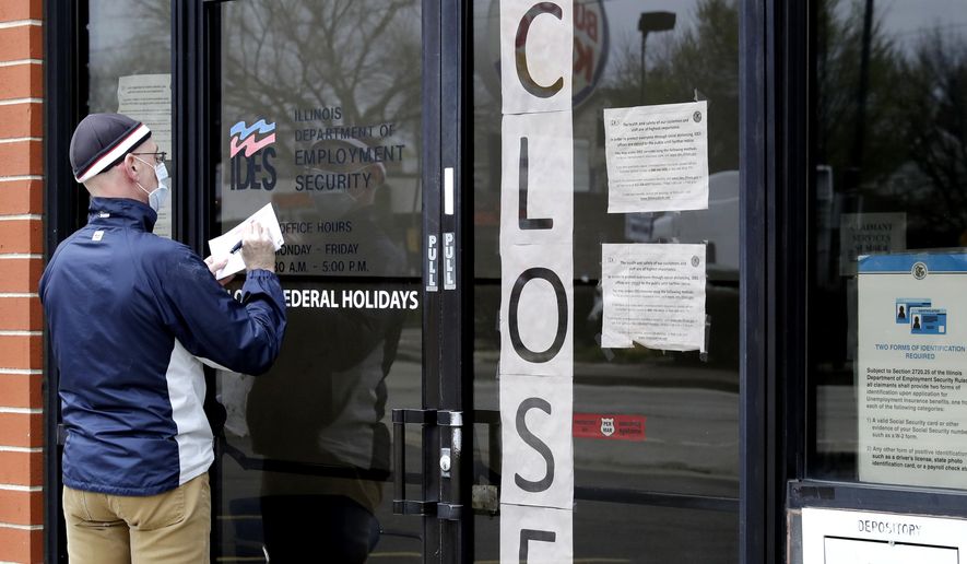 In this April 30, 2020, file photo, a man writes information in front of the Illinois Department of Employment Security in Chicago. (AP Photo/Nam Y. Huh, File)