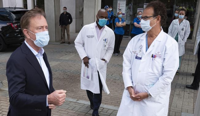 Connecticut Gov. Ned Lamont, left, talks with medical staff outside Saint Francis Hospital, Thursday, May 7, 2020 in Hartford, Conn. He made a visit to the medical center to thank the healthcare workers for their efforts during the coronavirus pandemic. (AP Photo/Mark Lennihan)