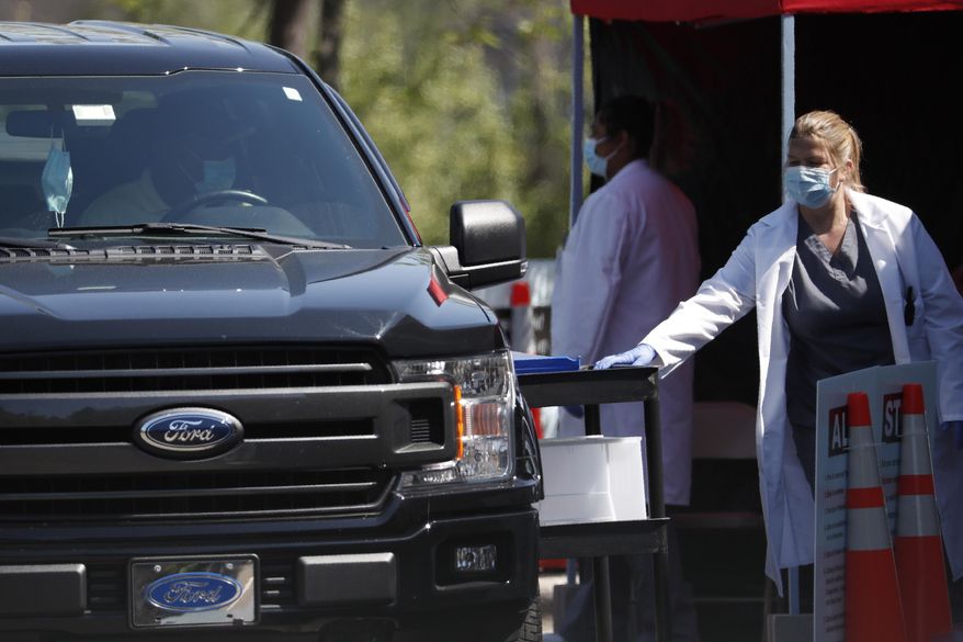 Cars approach a temporary COVID-19 drive-thru test site where patients administer their own test at a Walgreens in Durham, N.C., Thursday, May 7, 2020. Persons with appointments who meet certain criteria are assisted as pharmacists stand by. (AP Photo/Gerry Broome)