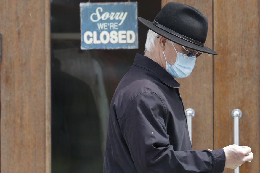 FILE - In this April 29, 2020 file photo, a man walks past a closed business in Shaker Heights, Ohio. Many people consider the Paycheck Protection Program that promised nearly $670 billion in forgivable loans to help companies rehire laid-off workers to already be a success because millions of businesses have gotten the money. But owners and business groups have said loans weren’t getting to companies most in need and it wasn’t arriving fast enough. (AP Photo/Tony Dejak, File)