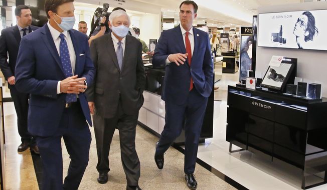 Oklahoma Gov. Kevin Stitt, right, walks with Dillard&#x27;s Vice President, Bill Dillard III, left, and Dillard&#x27;s CEO, Bill Dillard II, center, during a tour of Dillard&#x27;s at Penn Square Mall Friday, May 8, 2020, in Oklahoma City, the fourth day the store has been open since temporarily closing due to coronavirus concerns. (AP Photo/Sue Ogrocki)