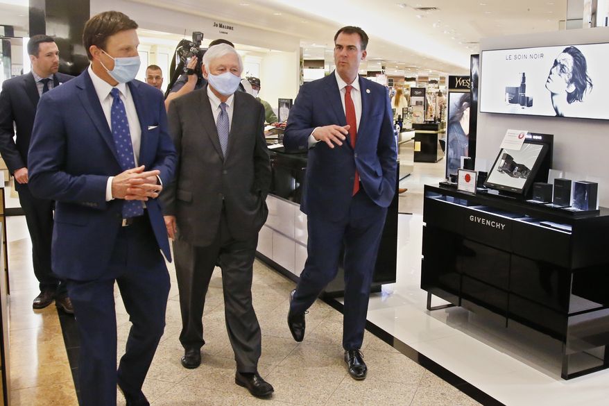 Oklahoma Gov. Kevin Stitt, right, walks with Dillard&#x27;s Vice President, Bill Dillard III, left, and Dillard&#x27;s CEO, Bill Dillard II, center, during a tour of Dillard&#x27;s at Penn Square Mall Friday, May 8, 2020, in Oklahoma City, the fourth day the store has been open since temporarily closing due to coronavirus concerns. (AP Photo/Sue Ogrocki)