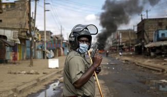 A police officer holds a pistol during clashes with protesters near a burning tyre barricade in the Kariobangi slum of Nairobi, Kenya Friday, May 8, 2020. Hundreds of protesters blocked one of the capital&#39;s major highways with burning tires to protest government demolitions of the homes of more than 7,000 people and the closure of a major food market, causing many to sleep out in the rain and cold because of restrictions on movement due to the coronavirus. (AP Photo/Brian Inganga)
