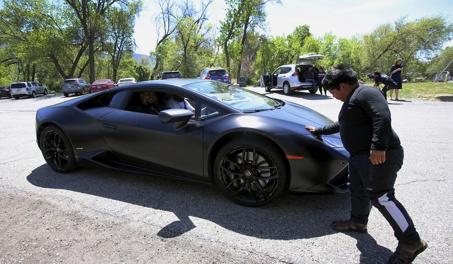 Adrian Zamarripa touches the front of Jeremy Neves' Lamborghini Huracan in Ogden, Utah, Tuesday, May 5, 2020. Adrian, who tried to drive his parents' car to California Monday and was stopped by the Utah Highway Patrol, got a ride on the Lamborghini Tuesday from Neves who heard about the news and drove his car from another county for Adrian. (Scott G Winterton/The Deseret News via AP)