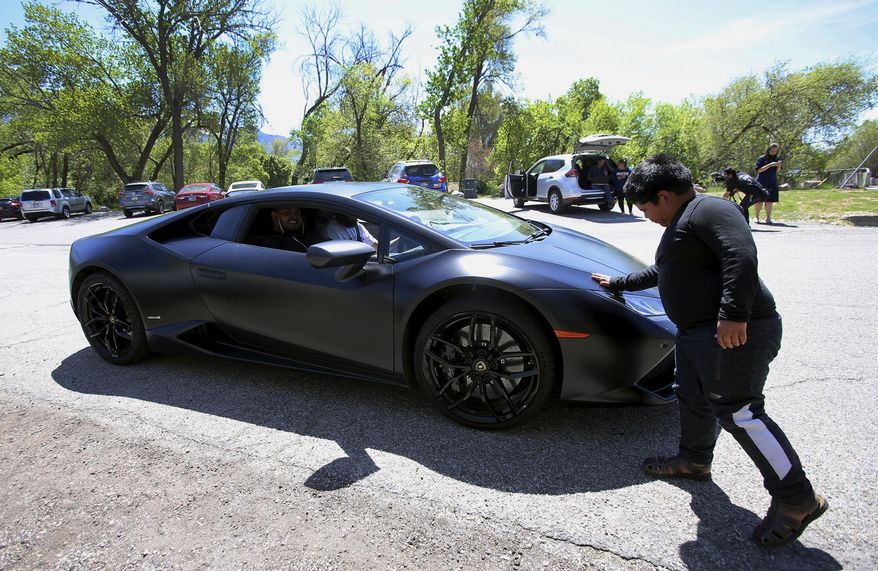 Adrian Zamarripa touches the front of Jeremy Neves' Lamborghini Huracan in Ogden, Utah, Tuesday, May 5, 2020. Adrian, who tried to drive his parents' car to California Monday and was stopped by the Utah Highway Patrol, got a ride on the Lamborghini Tuesday from Neves who heard about the news and drove his car from another county for Adrian. (Scott G Winterton/The Deseret News via AP)