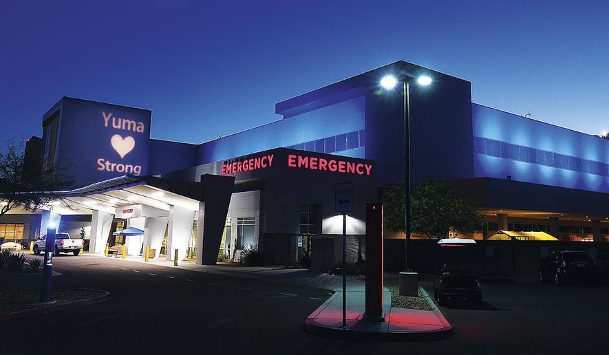 In this Wednesday, May 6, 2020, file photo Yuma Regional Medical Center&#x27;s Emergency Department upper-level exterior walls are bathed in blue light and a special sign, &amp;quot;Yuma Strong,&amp;quot; is projected on another wall as YRMC observes National Nurses Week in Yuma, Ariz. (Randy Hoeft/The Yuma Sun via AP) ** FILE **