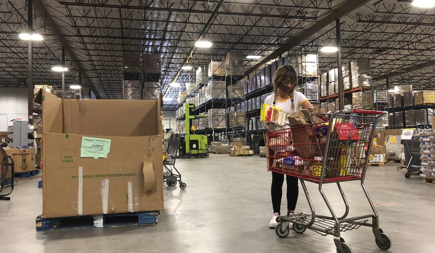 Volunteer Abigail Gold sorts food at Roadrunner Food Bank in Albuquerque, New Mexico, on Thursday, May 7, 2020, so it can be packaged and distributed to food pantries through the region as demand escalates. Gold is among the more than 133,000 New Mexicans who have had their unemployment claims processed by the state since mid-March. She said she wanted to help after being out of work for more than a month. (AP Photo/Susan Montoya Bryan)
