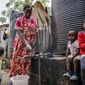 In this April 10, 2020, photo, Judith Andeka a widow and mother of five, fetches water with a bucket in the Kibera slum, or informal settlement, of Nairobi, Kenya. Andeka used to earn $2.50 to $4 a day washing clothes in Nairobi’s Kibera, one of the world’s biggest slums. With people not going to work because of restrictions on movement, neighbors can’t afford her services. (AP Photo/Brian Inganga)