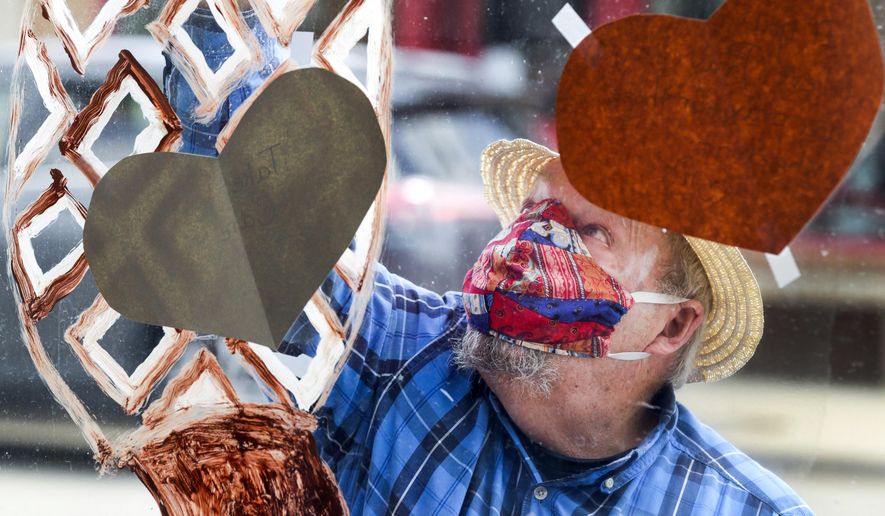 Ken Lewis of Cedar Rapids, Iowa, paints a morel mushroom on the window of his and his wife Pam's antiques mall in Cedar Rapids, Iowa on Thursday, May 7, 2020. The couple decorated the windows of their closed shop for what would have been this weekend's Houby Days festival to continue the spirit of the spring festival. The festival celebrates the history and culture of the Czech Village district of the city. The festival was cancelled due to coronavirus pandemic. (Jim Slosiarek/The Gazette via AP)