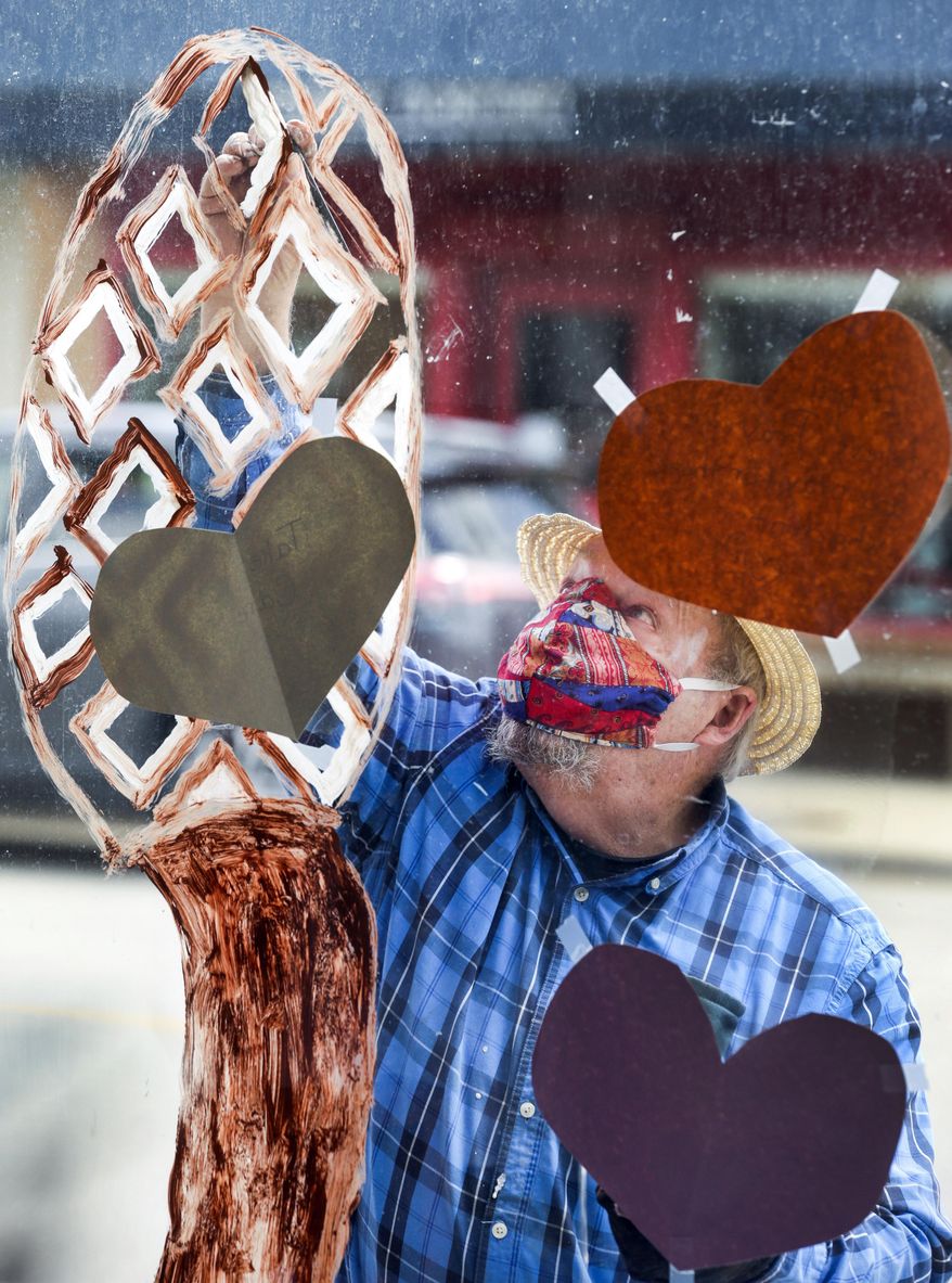 Ken Lewis of Cedar Rapids, Iowa, paints a morel mushroom on the window of his and his wife Pam's antiques mall in Cedar Rapids, Iowa on Thursday, May 7, 2020. The couple decorated the windows of their closed shop for what would have been this weekend's Houby Days festival to continue the spirit of the spring festival. The festival celebrates the history and culture of the Czech Village district of the city. The festival was cancelled due to coronavirus pandemic. (Jim Slosiarek/The Gazette via AP)