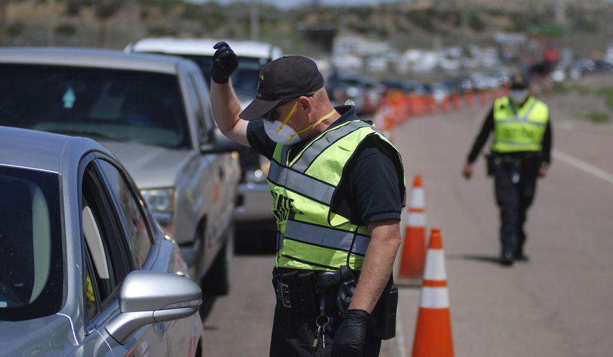 FILE - In this May 7, 2020, file photo, New Mexico state police officers screen cars for compliance with an emergency lockdown order that bans nonessential visitors and limits vehicle passengers to two people as they enter Gallup, N.M. New Mexico Sheriffs&#39; Association President Tony Mace and State Republican Party Chairman Steve Pearce each sent letters to U.S. Attorney General William Barr last week seeking a review into the health orders that have shuttered some businesses since late March. They allege the order, which has closed several small businesses, violates residents&#39; civil rights. (AP Photo/Morgan Lee, File)