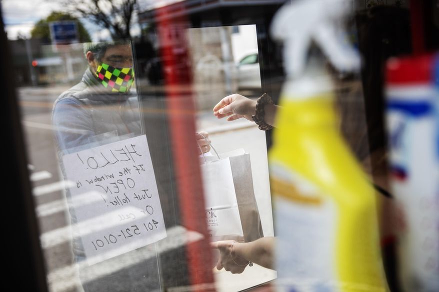 A customer picks up an order of household goods from a shop's walk up window Saturday, May 9, 2020, in Providence, R.I. Non-essential businesses are reopening under Gov. Gina Raimondo's plan to gradually lift some restrictions imposed to slow the outbreak. Face masks are now required for anyone in a public place and bars, salons and gyms remain closed while restaurants remain limited to take out and delivery. (AP Photo/David Goldman)