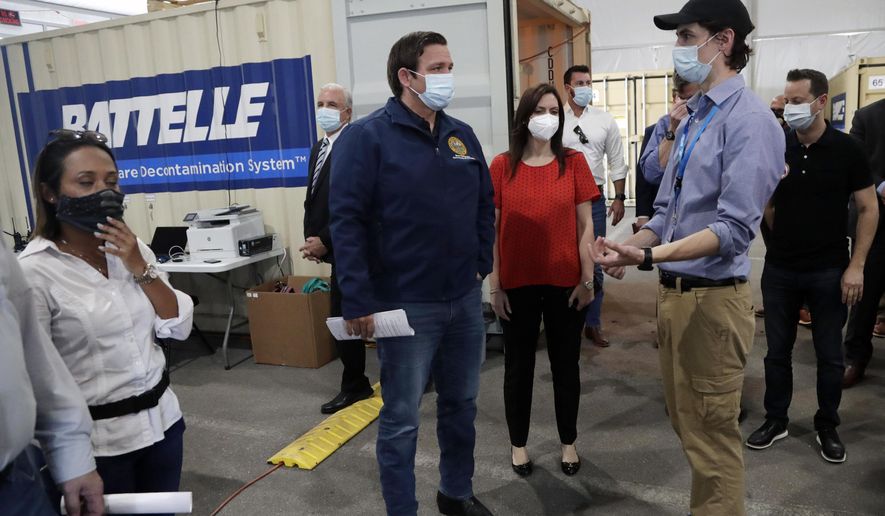 In this Wednesday, May 6, 2020, photo, Gov. Ron DeSantis, center, tours decontamination units at a COVID-19 testing site with Sean Harrington, of Battelle Critical Care Decontamination System, right, at Hard Rock Stadium, during the new coronavirus pandemic in Miami Gardens, Fla. Battelle decontaminates N95 masks used by health care workers and first responders. DeSantis, one of Trump’s closest allies, said at a news conference that one of the biggest problems the state faced when trying to obtain personal protective equipment is that much of it was manufactured in China and is slow to arrive. “All this stuff should be made in the United States and not in China. We don’t want our health destiny resting in the hands of a communist dictatorship,” DeSantis said. “We would certainly welcome any of the manufacturing of the masks, the PPE kits, whatever you are doing. Come to Florida.” (AP Photo/Lynne Sladky, Pool) **FILE**