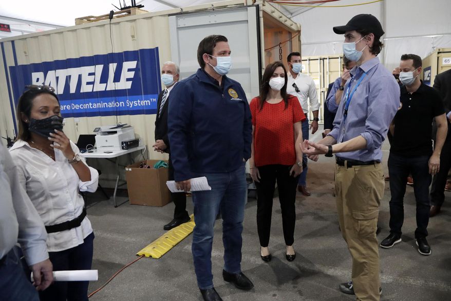 In this Wednesday, May 6, 2020, photo, Gov. Ron DeSantis, center, tours decontamination units at a COVID-19 testing site with Sean Harrington, of Battelle Critical Care Decontamination System, right, at Hard Rock Stadium, during the new coronavirus pandemic in Miami Gardens, Fla. Battelle decontaminates N95 masks used by health care workers and first responders. DeSantis, one of Trump’s closest allies, said at a news conference that one of the biggest problems the state faced when trying to obtain personal protective equipment is that much of it was manufactured in China and is slow to arrive. “All this stuff should be made in the United States and not in China. We don’t want our health destiny resting in the hands of a communist dictatorship,” DeSantis said. “We would certainly welcome any of the manufacturing of the masks, the PPE kits, whatever you are doing. Come to Florida.” (AP Photo/Lynne Sladky, Pool) **FILE**