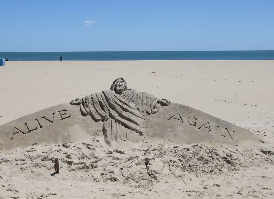 A sand sculpture designed by boardwalk evangelist Randy Hofman depicts Jesus Christ rising along with the words "Alive Again" on the beach in Ocean City, Md., on Saturday, May 9, 2020. The resort town reopened its beach and boardwalk on May 9 after almost two months closed due to the coronavirus pandemic. (Photo by All-Pro Reels / Ed Sheahin)