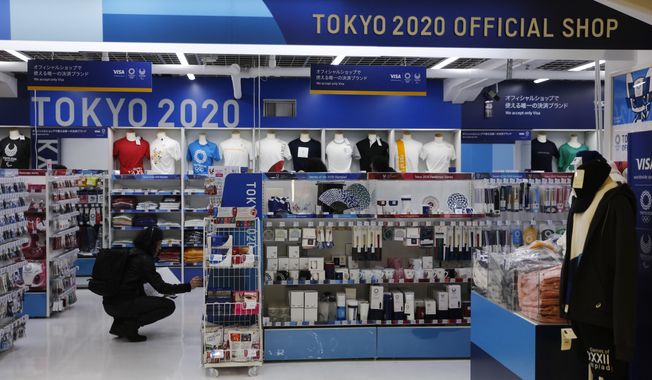 In this Jan. 8, 2020, file photo, a man looks at Olympic souvenirs at a Tokyo 2020 official shop in the Shinjuku district of Tokyo. Official Tokyo Olympic souvenir shops are drawing few customers these days. The pandemic and the fact the Olympics have been postponed for a year has wiped out almost all business. (AP Photo/Jae C. Hong, File)
