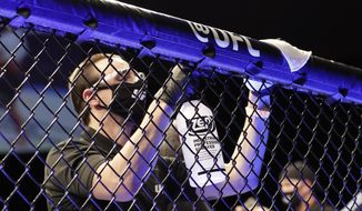 A worker wipes down areas of the octagon between bouts at a UFC 249 mixed martial arts event Saturday, May 9, 2020, in Jacksonville, Fla. (AP Photo/John Raoux) **FILE**
